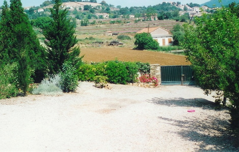 Par delà le portail, vue sur les restanques et le bassin d'irrigation